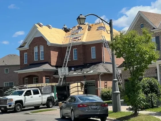 Crew re-shingling a large two-storey brick home
