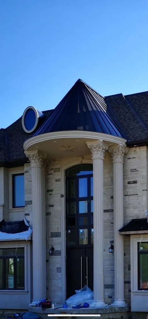 Black metal turret roof over a stone entranceway
